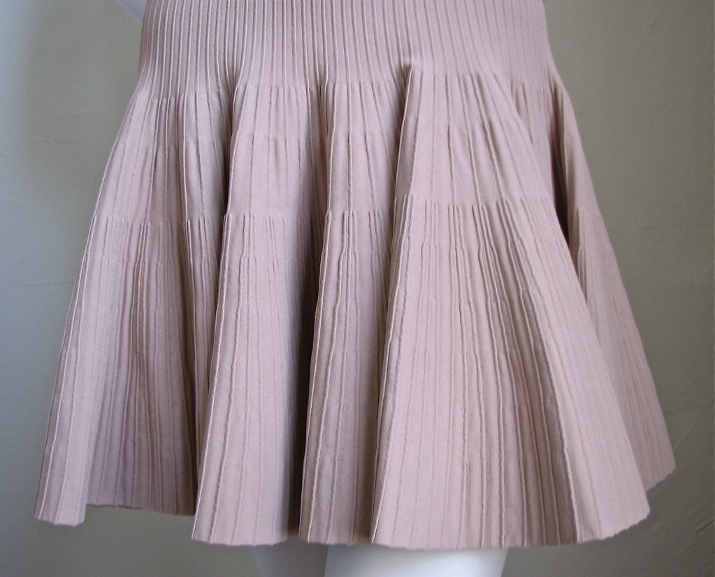 Exceptionally flattering and very versatile knit dress from Alaia. Looks great worn casual or formal. Color is blush (slightly nude). V-neckline. Dress zips up back. Size M. Best suited for a US 4 or 6. Made of very stretchy fabric that shapes the