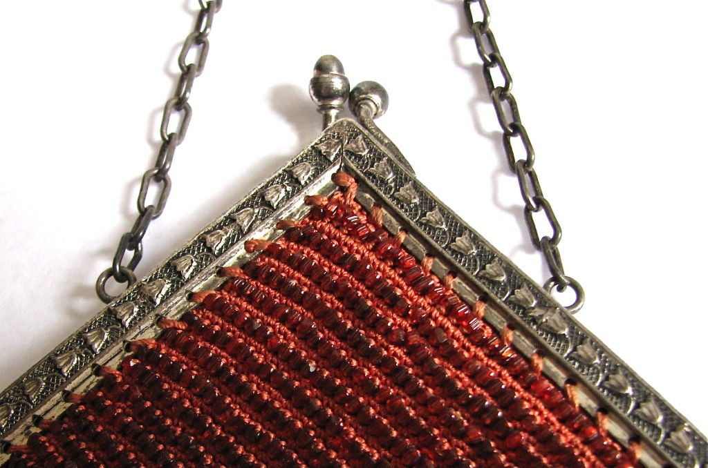 Stunning copper toned faceted beads make up this uniquely shaped evening purse. Heavy twisted fringe. Ornate silver toned frame with tulip motif. Fully lined in silk with floral trim. Excellent condition.