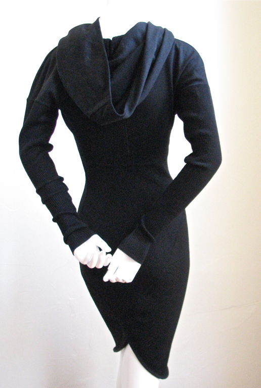 Very rare hooded dress from Alaia. Flattering asymmetrical seams. 'Hood' can be draped for a more conventional look. Arms are made of a contrasting ribbed wool and are very long and narrow. Labeled a size 'S'. Jet black in color. Made of wool with