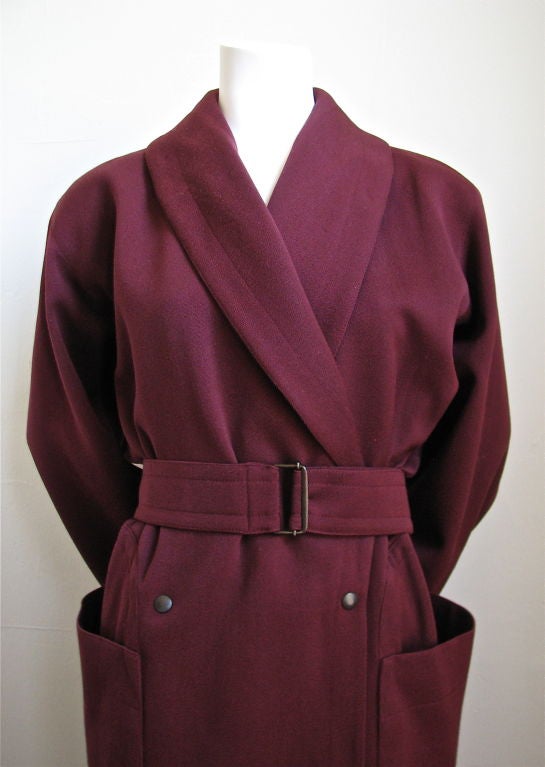 Beautiful wine toned gabardine coat with oversized wrap around pockets from Azzedine Alaia dating to the 1980's. Darting at waistline for a flattering fit. Best suited for a US size 4/6. Fully lined. Snap closure with adjustable belt at waist.