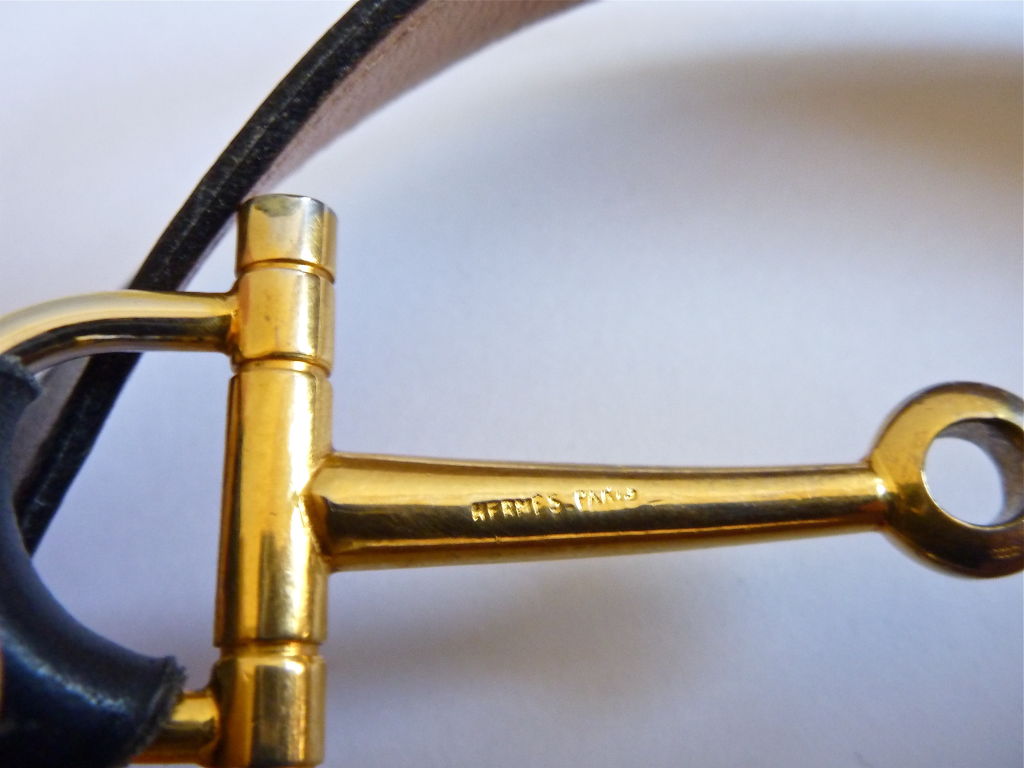 Rare leather belt with horse bit motif from Hermes dating to approximately 1985. Navy leather with gilt metal. Buckles in back. Fits a 26