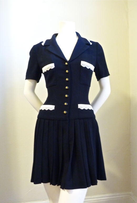 Very chic, extremely flattering mini dress from Chanel. Dark navy blue (almost black) with white trim. FR size 38. Best for a US 4. Buttons up front with 7 large navy blue and gold buttons. Two pockets at hips and two pockets at chest. Wool. Fully
