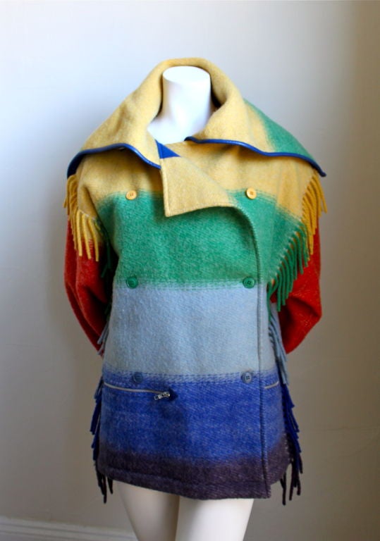 Very fun, brightly colored blanket jacket from Jean-Charles de Castlebajac. Ca. 1985. Fringe detail along sides. Leather accents. Zippered pockets at hips. Adjustable collar. Fully lined in royal blue felted wool. Best suited for a small or medium