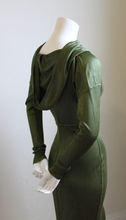 Very rare hooded dress from Alaia. 'Hood' can be draped for a more conventional look. Arms are made of a contrasting ribbed wool and are very long and narrow. Labeled a size 'S'. Olive green in color. Made of a viscose with stretch. Zips up center