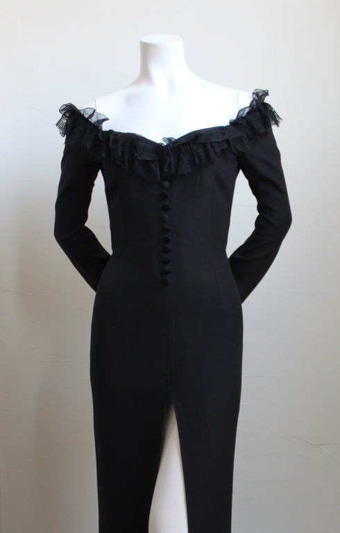 Black crepe couture gown with extra high center front slit From Christian Dior dating to the 1980's. Gown has a beautiful hidden corset and is accented with an off the shoulder neckline trimmed in lace. Unique satin button detail up the center