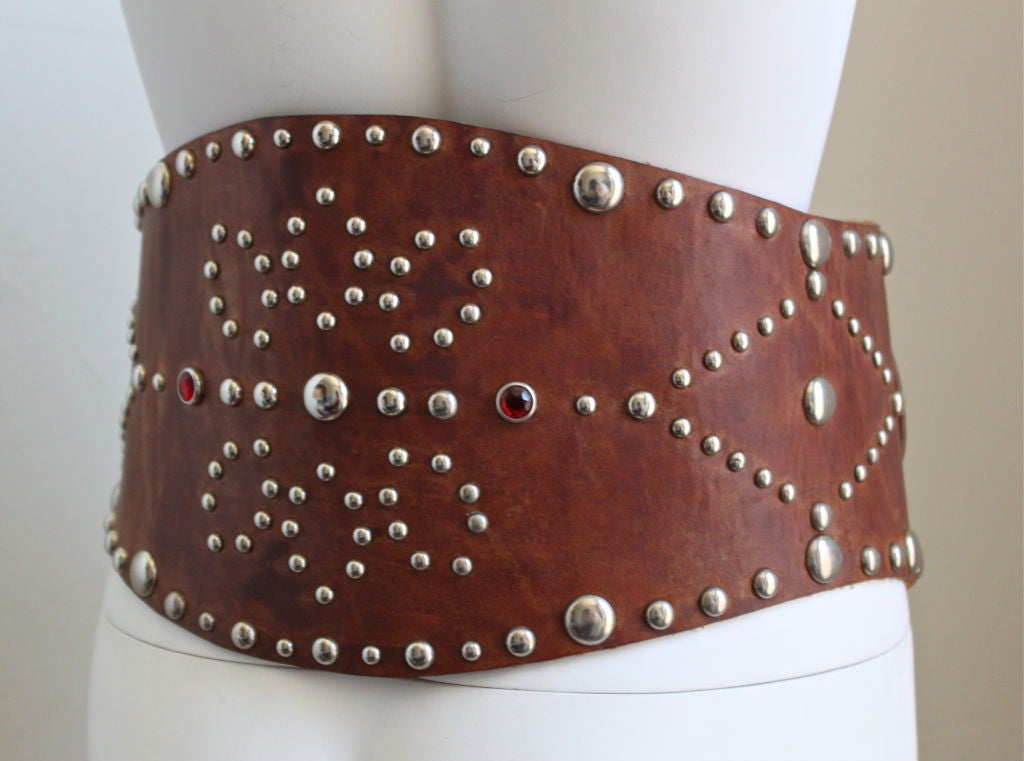 Very rare brown leather corset belt with silver studs from Ralph Lauren dating to the 1970's. Two red faceted glass stone accents at back. Gorgeous rich brown patina. Very thick leather. Belt comfortably fits a 26-29