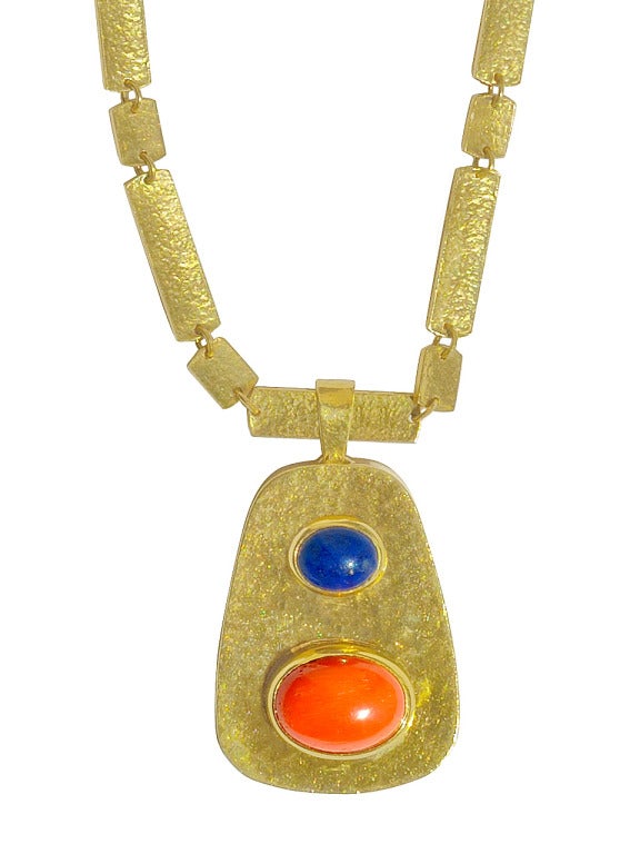 18 kt. gold textured and hammered  pendant,set with a lapis and coral cabochon. The pendant is suspended from a neck chain, consisting of hammered and textured rectangle and square links. Signed BORIS.

Chain is 18