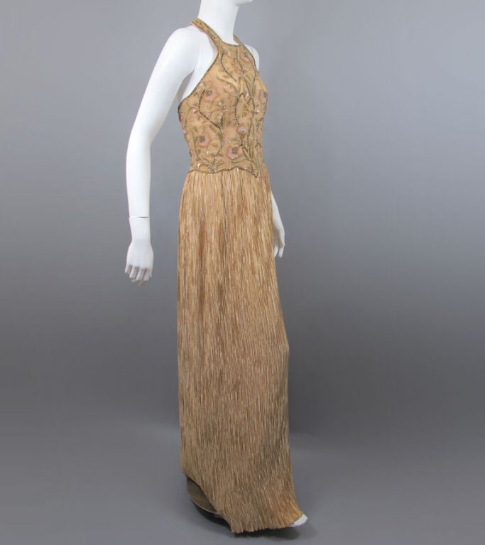 Mary McFadden Couture luxurious evening gown of beaded halter top and signature McFadden accordian pleated skirt.  A rich deep champagne (with apricot hue), the gown has a halter neckline (with three hidden hook-eye back closure); the tapered boned