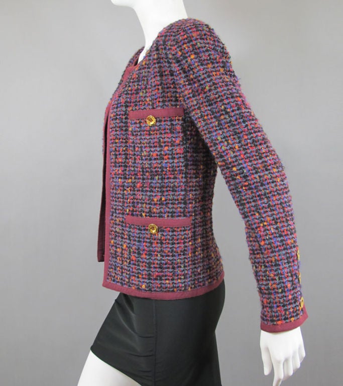CHANEL circa 1980s tweed wool boucle jacket of burgundy with yellow, blue, orange, purple, green, black, red, etc. tweed.  The jacket is a classic 1980s style with round neckline, open front, four front pockets (with gold Chanel Paris buttons), and