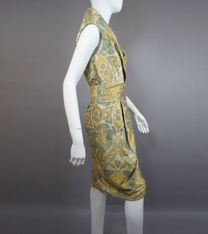 Alexander McQueen fall 2006 runway dress in a heavy jacquard silk paisley of beige, gold and green with silk lining.  The dress has a high back collar, crossover wrap bodice, belted waistband, and straight gently gathered at the waist skirt.  Hidden
