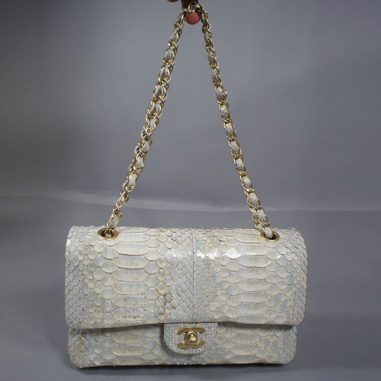 Chanel 2.55 in silver colored python skin, with a gold dusted sparkle on the python scales and iridescent sheen. This exotic double-flap handbag features gold tone hardware with front Chanel CC turn-lock closure. This bag is a silver color with