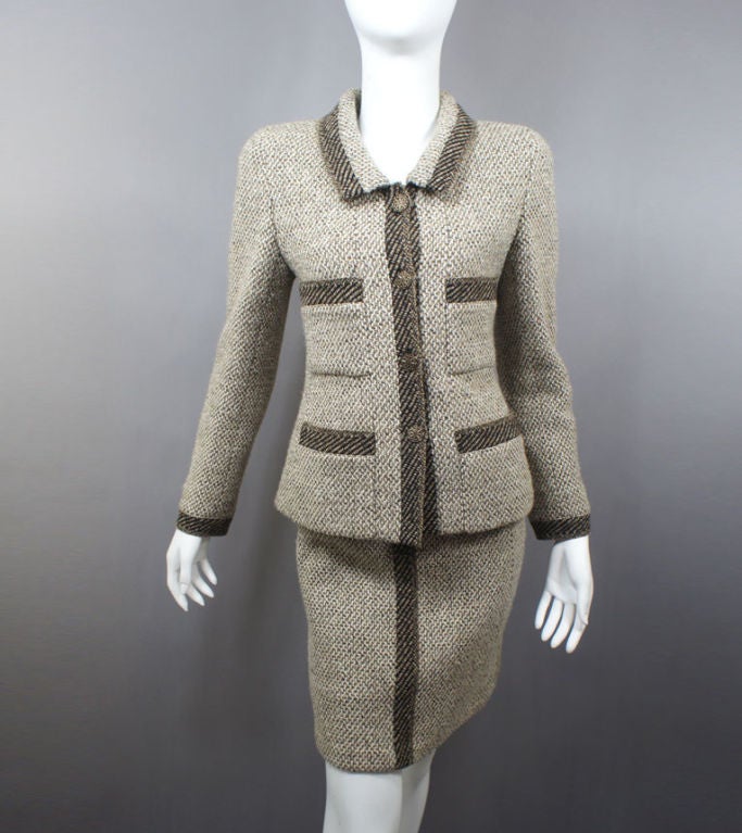 CHANEL skirt suit in cream & camel tweed boucle wool with dark trim detail (black & camel) on pockets, collar and cuffs from 98A. This signature CHANEL look features a collar, four rustic CC button front closures, two breast pockets and two hip