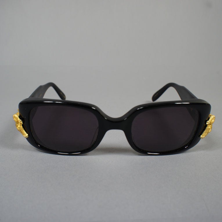 Kieselstein Cord black sunglasses, stamped with the style 'Gatorville,' has gold-toned alligators at each side.  The shape is a stylish oval with a slight squaring, with a 3/4