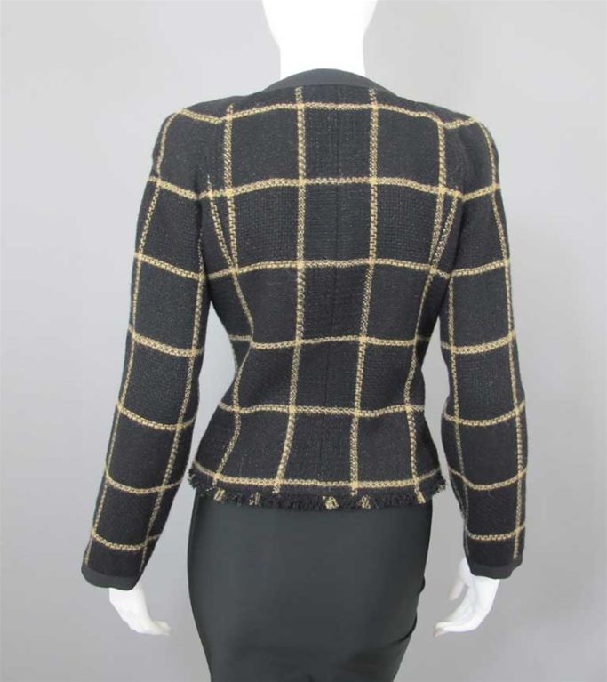 Chanel black and gold wool boucle in a windowpane pattern.   The jacket has a round neckline, front hidden zipper close, two hip-level patch pockets with gold sunburst logo buttons and long sleeves.  Neckline, front, pockets, sleeves and cuffs are