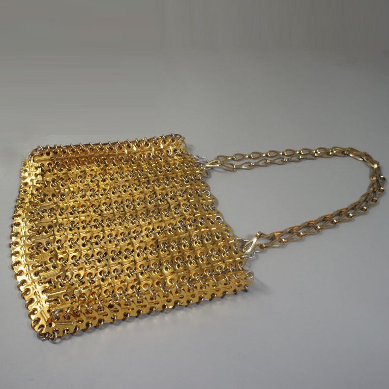 Paco Rabanne's original '69 Icon chain mail bag in shiny gold aluminum (crafted from metal used in lavatories). The discs are gold-tone metal, while the hooks are silver aluminum. This bag lies flat when not stuffed or in use, as it is made