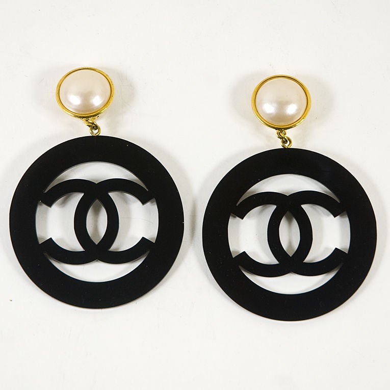 CHANEL vintage hoop earrings from the 1988 collection featuring black lucite CC logo design in circle with with large faux pearl at the top. These iconic beauties immediately say Chanel to any passerby and will enhance any elegant outfit. Comes in