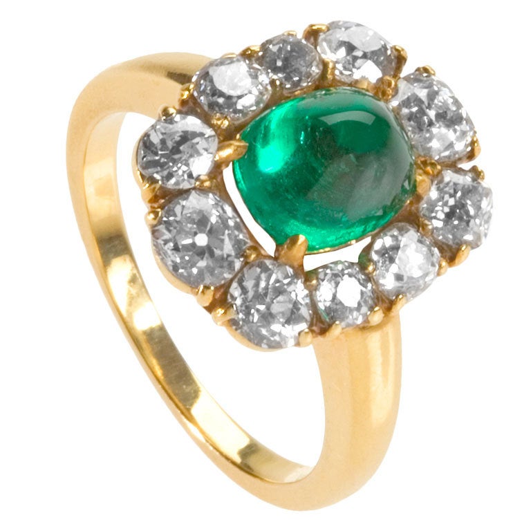 An American 18 karat gold, diamond and cabochon emerald ring by Raymond Yard. The cluster ring centers on a sugarloaf Colombian emerald weighing approximately 2.10 carats, surrounded by 10 old-mine cut diamonds weighing approximately 1.30 carats.