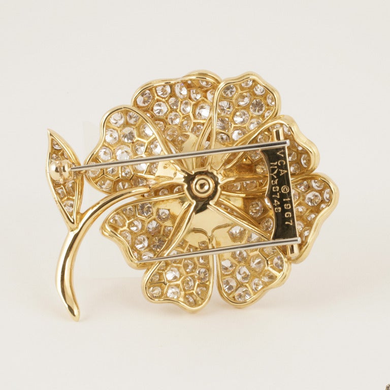 A Mid-20th Century 18 karat gold flower brooch with diamonds by Van Cleef & Arpels. The 3-dimensional flower petals contain 96 round-cut diamonds with an approximate total weight of 6.00 carats, G-H color and VS clarity grade.  

Signed, VCA 1967