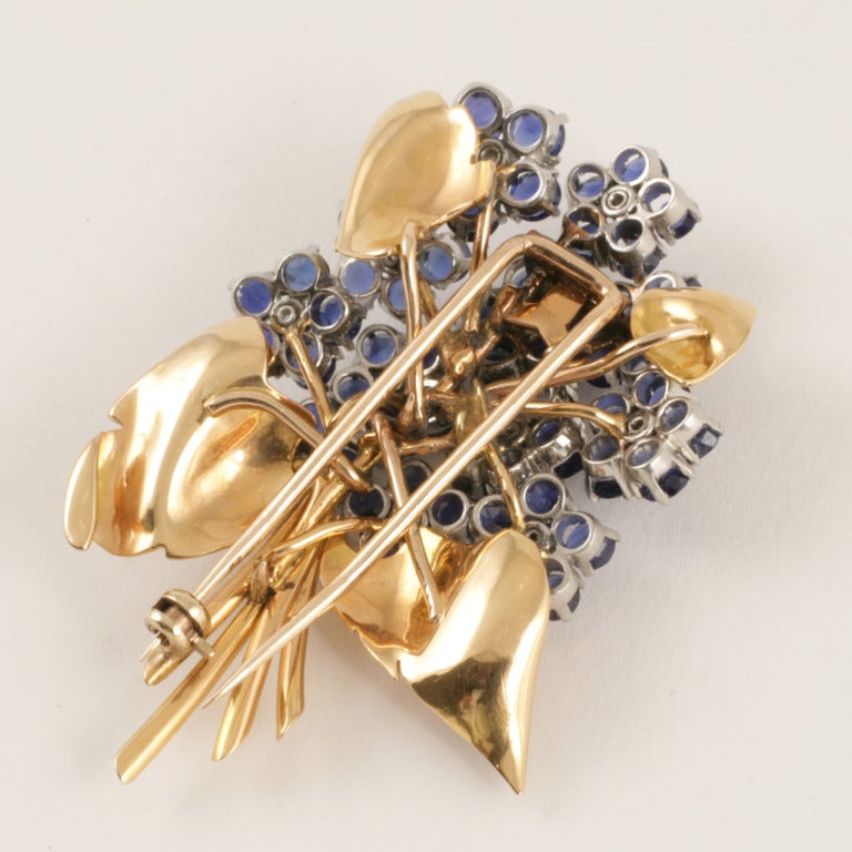 An 18 karat gold and platinum flower bouquet brooch with sapphires and diamonds. The brooch has 60 sapphires with an approximate total weight of 9.00 carats, and 12 diamonds with an approximate total weight of .84 carats.  

Circa 1940. 

(MG