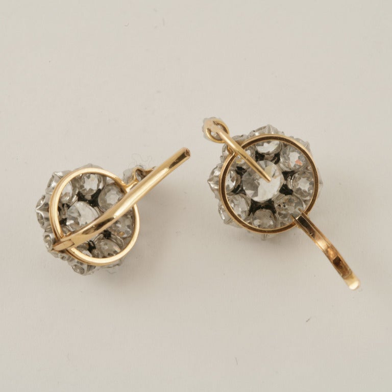 A pair of French Antique 18 karat gold and platinum cluster flower earrings with diamonds. The earrings feature 20 old mine-cut diamonds with an approximate total weight of 6.70 carats. (Center diamond weighs approximately 1.25 carats each)