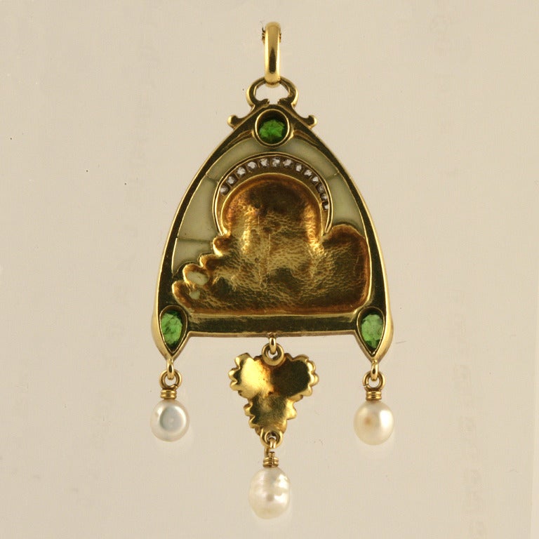 A French Art Nouveau 18 karat gold pendant with diamonds, pearls and peridots. The pendant features a plique-à-jour background with rose-cut diamonds with an approximate total weight of .60 carat, 3 freshwater pearls and 3 pear and round-cut