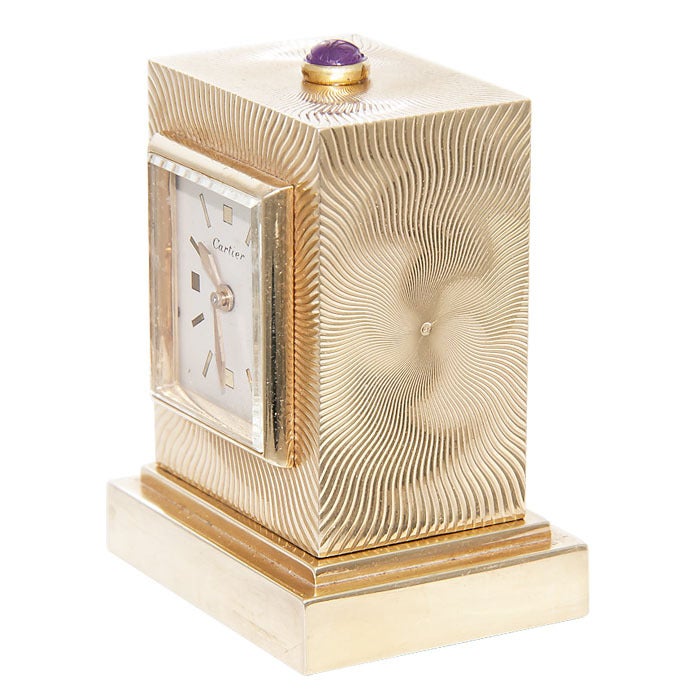 Cartier, Circa: 1950 14K Yellow Gold Cased Desk Clock. 8 Day Geneve Clock Company Movement. Engine Turned case, top set with a carved Cabachon Ruby. Original Dial, case signed and numbered.