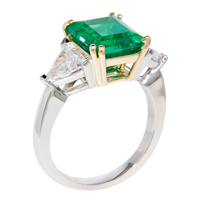 Platinum Ring set with a Very Fine Step Cut Emerald of 3.86 Carats and 2 Side Trillion Diamonds that total 1.20 Carats G Color VS Clarity. The Emerald was originally purchased from Neiman Marcus and has certificate numbers. Finger size = 6 1/2.