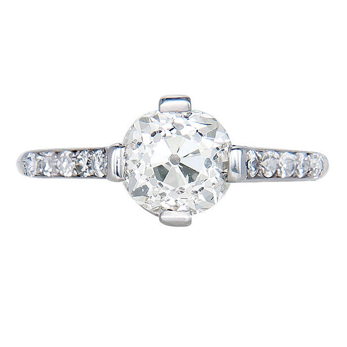 Circa: 1920 Platinum Engagement ring set with an Old Cushion Cut Diamond weighing 1.60 Carat, L Color and VS 2 Clarity. The sides of the Mounting are further set with small old cut Diamonds.  Finger size = 6