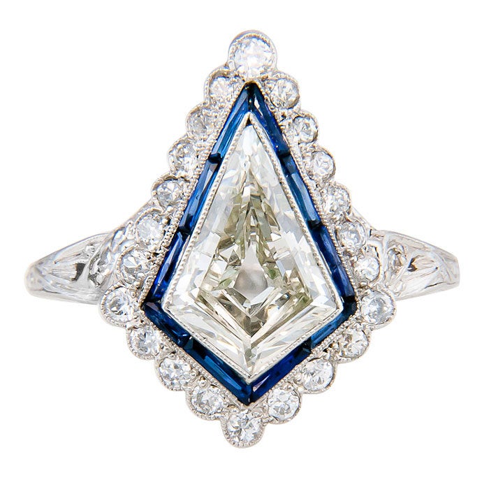 Unique Kite Shape Diamond Ring, circa: 1920s  in a Platinum mounting. Weighing 1.10 Carat this Diamond looks and spreads much Bigger and is surrounded by Baguette Sapphires and further surrounded by smaller old cut Diamonds as well as old cut Round