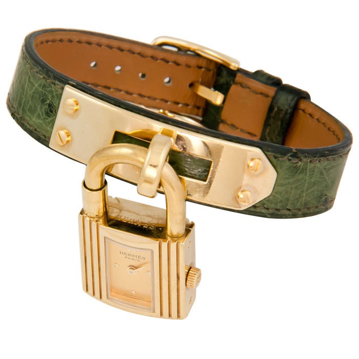 Lady's Kelly lock-form wristwatch by Hermes. Gilt metal case and strap fittings. Green textured strap. Quartz movement. Very minor wear to the strap. With original service booklet.