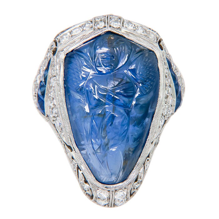 Circa: 1930 Art Deco, Platinum, Diamond and Sapphire Ring.  Centrally set with a fine color Carved Sapphire, depicting a winged Figure. Fine Hand Made Platinum Mounting set with Diamonds and Sapphires. A fine Period and True Art Deco Ring, Finger