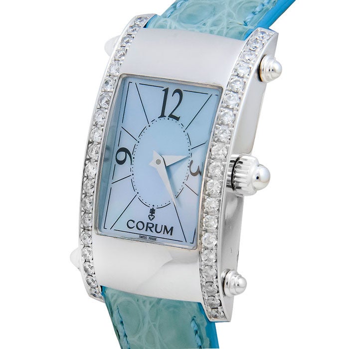 Corum lady's 18k white gold and diamond wristwatch, circa 2010. This relatively new and unworn watch has a blue mother-of-pearl dial, quartz movement, blue crocodile strap with white gold buckle, large wood presentation box and open warranty card.