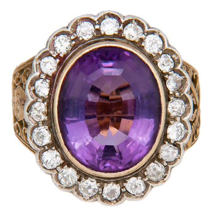 Circa: 1930s 18K yellow Gold Bishops Ring. Centrally set with an Oval Amethyst  Approximately 12 to 14 Carats and surrounded by approximately 2 Carats of old Mine Cut Diamonds. The sides feature very fine hand engraved detail work. Finger size = 12