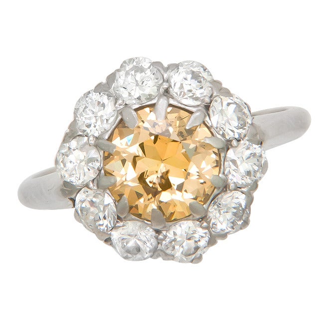 Circa: 1920 Platinum Ring centrally set with an Old European Cut Diamond weighing 1.10 Carats and Grading as A Fancy Brownish Yellow in Color and I1 in Clarity. Further surrounded by 1 Carat of Old European cut Diamonds that are F in color and VS to
