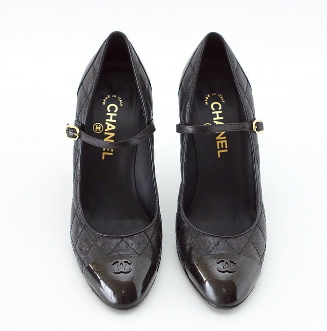 Guaranteed authentic CHANEL stunning black Mary Jane style pump.
Fabulous black textured leather quilted pump with a thin strap across the foot with gold CHANEL embossed buckle.
Rounded toe covered with black subtly sparkled hard cap with CC at