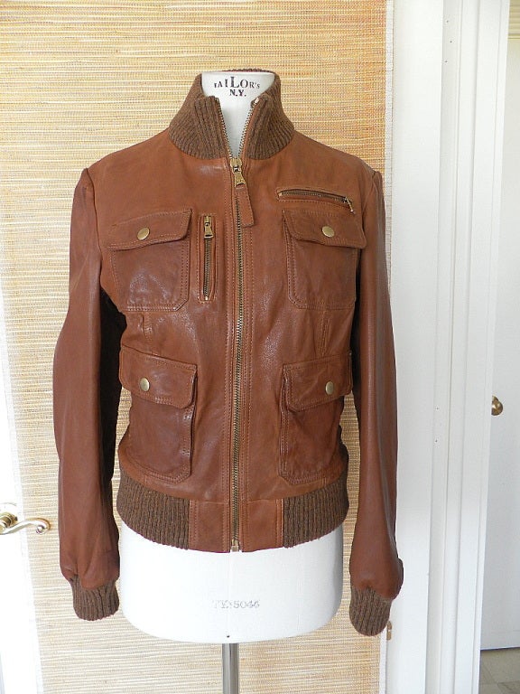 Fabulous bomber style leather jacket in a rich cognac.
Zip front with leather pull and D&G embossed on hardware.
Cognac subtle tweed knit collar, cuffs and waistband.
4 flap pockets with brass snaps.
1 verticle and one horizontal zip pockets