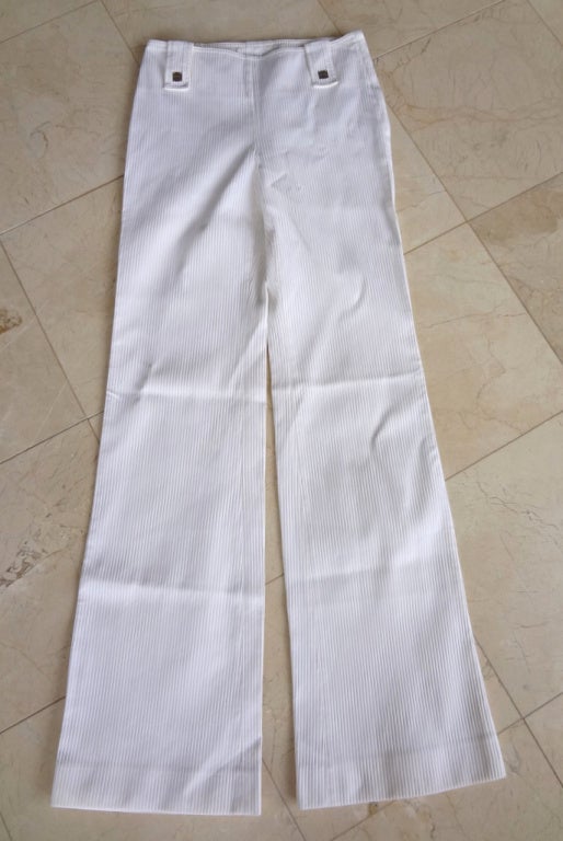 Guaranteed authentic Chanel 01P milk white pant. 
Narrow flat front cut over the hip with a flare leg.  
Waist has over sized 'tabs' - 2 in front and 3 in rear.
Front tabs have silver squares embossed CHANEL. 
Fabric is cotton and nylon.  
Unlined.