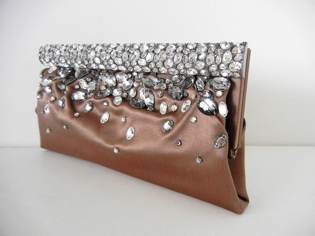The front of this frame top taupe satin evening bag is encrusted with various size and shape clear and smokey grey diamantes. 
The front of the frame is a solid 1 1/4