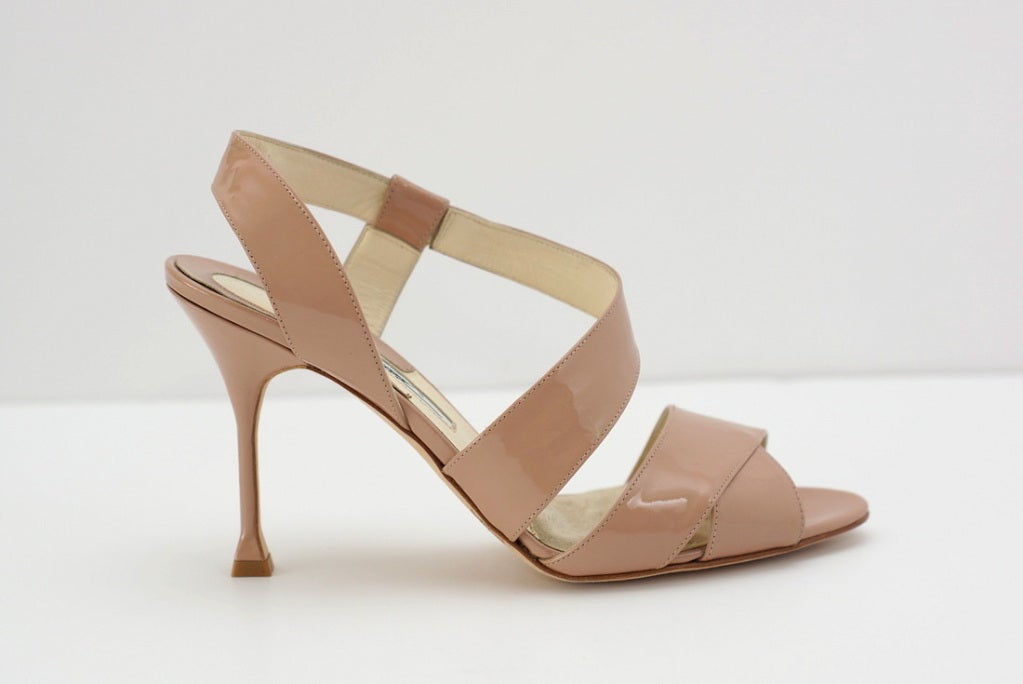 Nude patent leather strappy sandal.
Wide front strap with a criss cross affect.  
Separate strap comes from outer side of foot and wraps around the inside and around the heel creating a slingback. 
High thin patent heel with lovely shape detail
