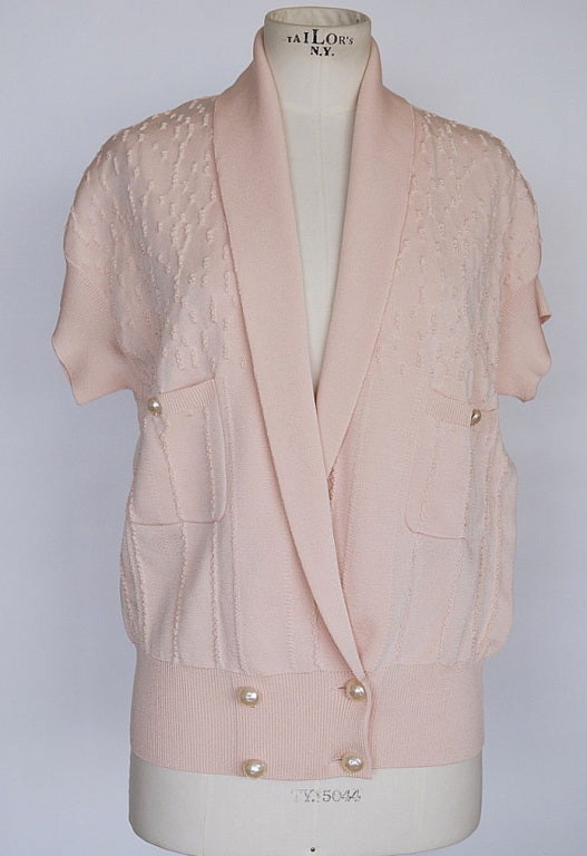 2012P short sleeved textured cardigan with plunging V neck and shawl collar.
2 Pockets and each with a button.
4 front buttons - all buttons are large faux pearl with small gold CC.
Textured ribbon accentuated the fabric.
Comes with 3 extra