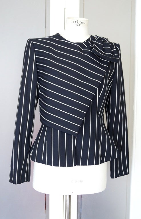 Guaranteed authentic GIORGIO ARMANI Beautifully shaped and detailed bold pinstripe jacket.
Fabulous fabric is a black on very dark navy stripe with white pinstripes. 
Hidden zipper front with a flap of fabric that fold across to the shoulder with