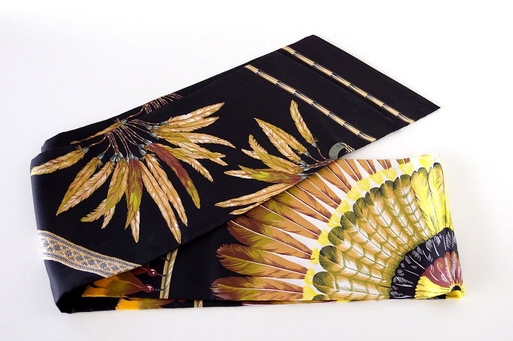 Striking new style large silk Le Maxi Twilly in a beautiful feather print.  
Black with gold, brown, tan, green and yellow. 
Signed by LB.  
HERMES PARIS is on the scarf. 
Lush size and selling out fast!
Comes with original tube shaped Hermes