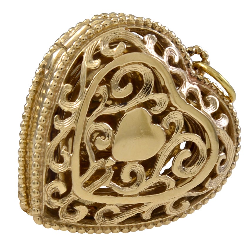 Wonderfully detailed 14K gold heart locket with flower center. The flower has rubies and an emerald. Pierced work around inner heart.
The heart opens to reveal  six heart frames that hold six pictures for loved ones.The reverse side has beautiful