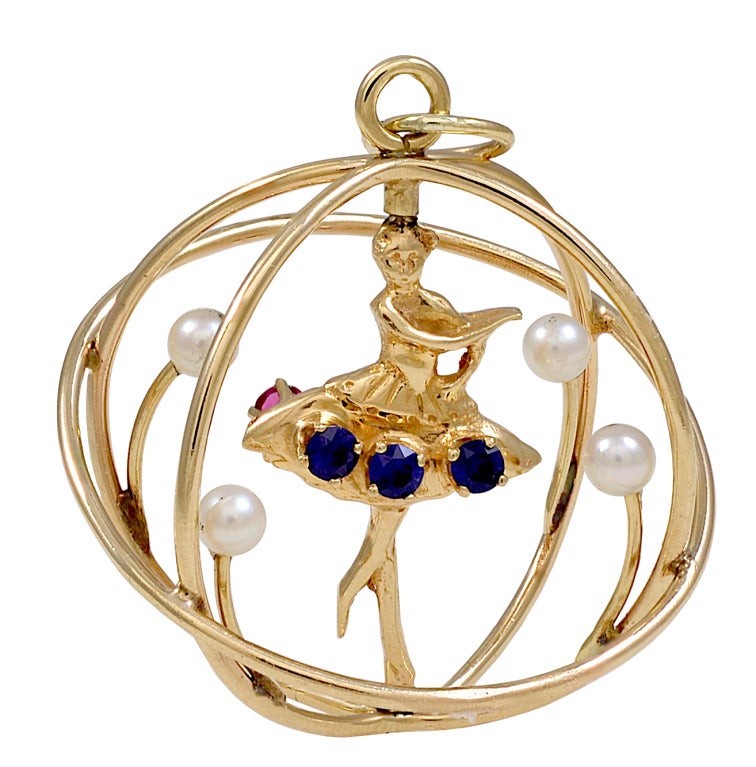Large moveable 14k gold gemset ballerina charm.Set with three faceted rubies in the front of the tutu.The ballerina spins around to reveal three faceted sapphires on the back of the tutu. She is surrounded by a casing set with pearls. This is a
