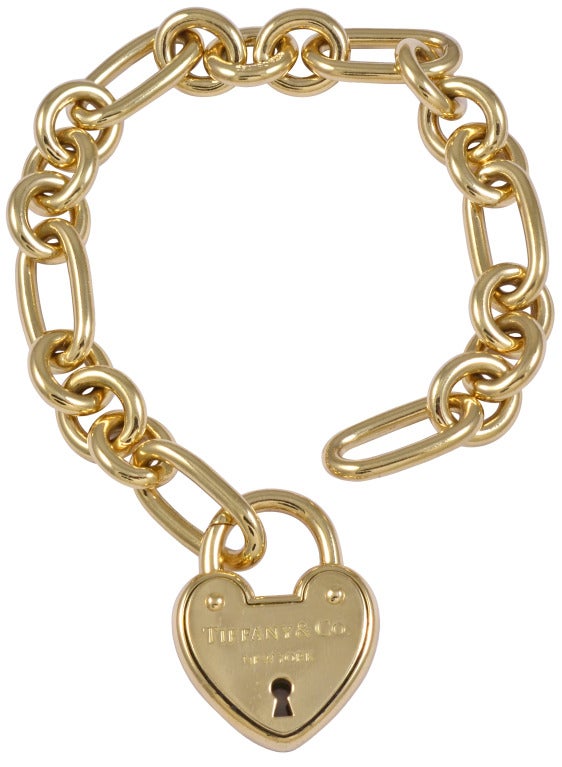 Large heavy 18k gold charm bracelet made by Tiffany& CO. 
The closure is a figural heart lock.
A beautiful silky link and a beautiful look.
Alice Kwartler has sold the finest antique gold and diamond jewelry and silver for over 40 years. Come and