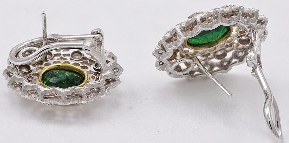 Large and luminous emerald and diamond earrings.  Made and signed by MARIO BUCCELLATI.  18K white and yellow gold.  The diamonds, approximately 2.15 cts. total weight, are set in a cut-out lacey pattern and surround a bright faceted emerald,