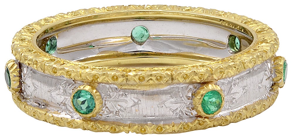Mario Buccellati 18K gold yellow and white band set with 7 brilliant faceted emeralds. The yellow gold banding frames the ring. This lovely ring has the distinctive Buccellati look. Size 61/2