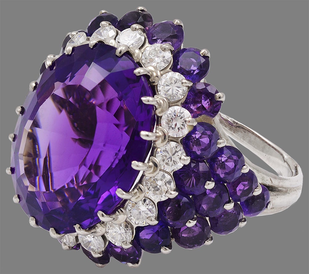 Gorgeous cocktail ring. Center amethyst is 15 cts. Vibrant purple color. 

Surrounded by 1.8 cts of sparkling white diamonds. Smaller faceted amethysts wrap around the sides of the ring. Set in 18k white gold. Size 7 1/2  and can be custom-