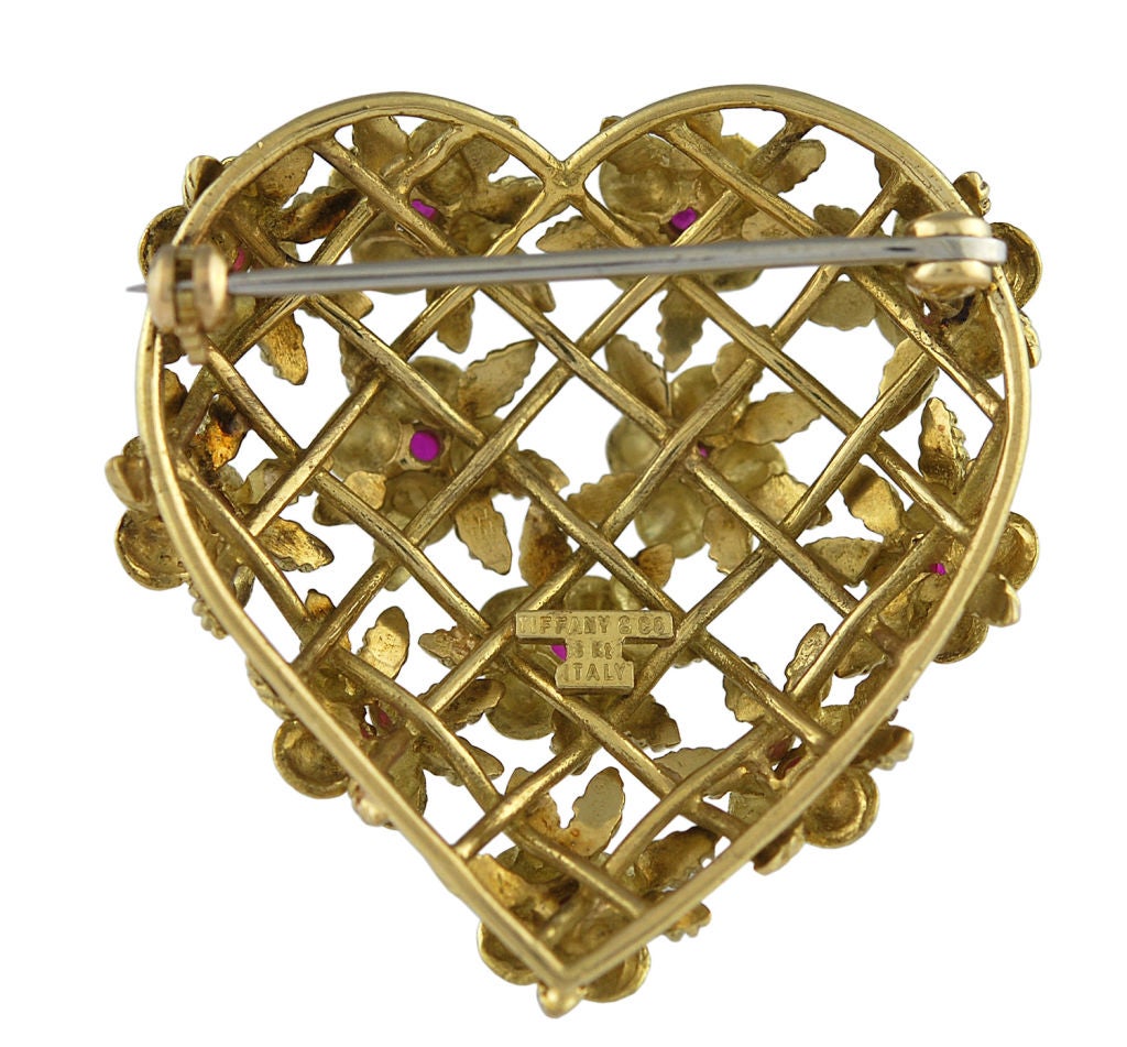 Lovely Tiffany& Co. heart shape brooch, 18K gold, flowers with faceted ruby centers set in fine latticework pattern.This brooch puffs out a bit so it has a lovely curvature