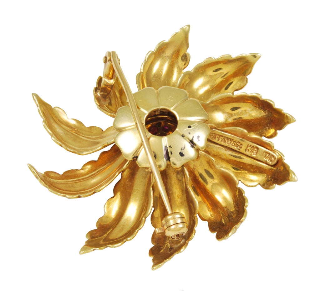 18k gold flower brooch signed TIFFANY. 
Finely textured leaves, set in pinwheel pattern, centered with 20 faceted rubies.Cheerful and wearable!